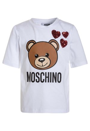 Biała koszulka z krótkim rękawem z grafiką brązowego niedźwiedzia, czarnym napisem "MOSCHINO" oraz trzema czerwonymi cekinowymi sercami na górnej lewej części.