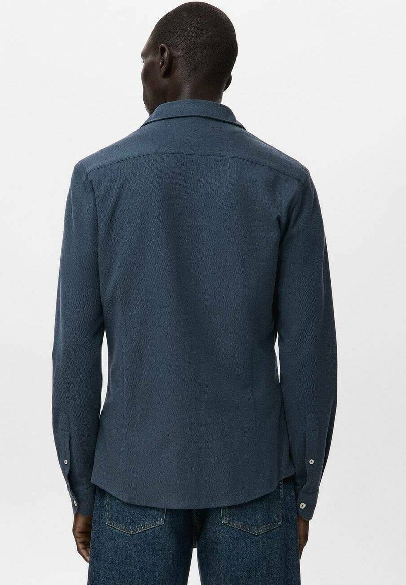 Mørkeblå vævet skjorte med spredt krave, lange ærmer og knaplukket ærmekant, fremstillet i et struktureret stof og med en let buet kant.