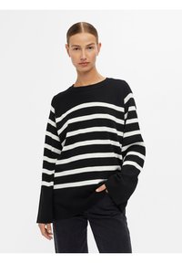 Maglione a righe bianche e nere in morbido tessuto a maglia, con scollatura rotonda e vestibilità rilassata, maniche ampie e design con spalla scesa.