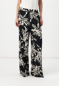 Pantaloni largi, confecționați dintr-un material ușor, cu un fond negru și modele florale mari, albe, având o talie elastică.