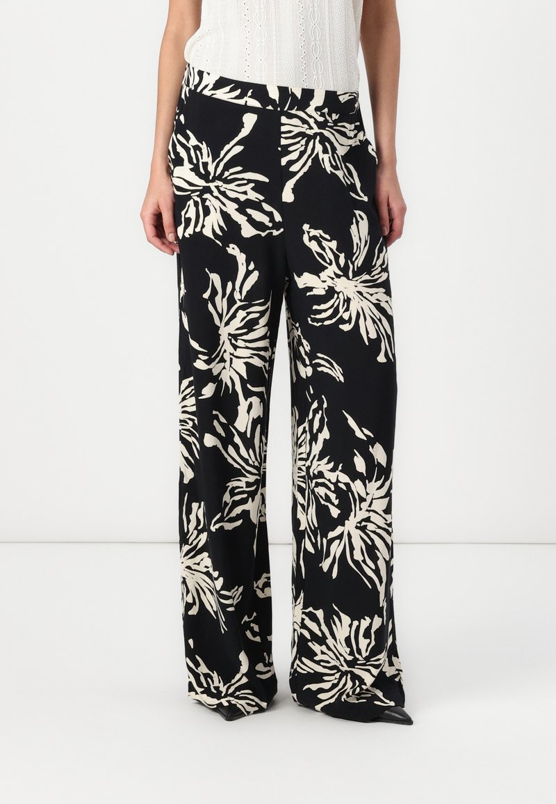 Pantaloni largi, confecționați dintr-un material ușor, cu un fond negru și modele florale mari, albe, având o talie elastică.