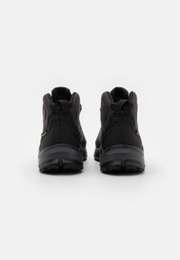 Schwarze Wanderschuhe mit hohem Schaft, einem strukturierten Obermaterial, verstärkter Ferse und robust profilierter Außensohle für besseren Halt.