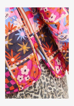 Kurtka pikowana z jaskrawym wzorem kwiatowym w odcieniach różu, pomarańczy i niebieskiego, z kontrastowym stębnowaniem i zaokrąglonym dołem.