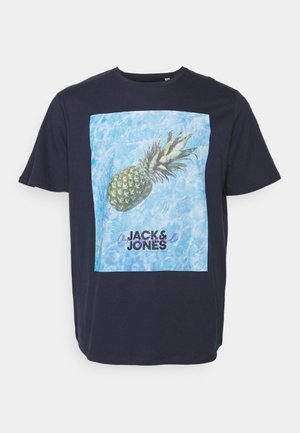 Camiseta azul marino con un gran gráfico de una piña sobre un fondo azul claro. Texto "JACK & JONES" en negro debajo del gráfico.