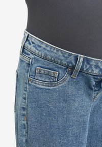 Pantalones vaqueros de mezclilla azul con un corte clásico, que cuentan con un bolsillo delantero, trabillas para el cinturón y costuras de contraste a lo largo de la cintura y las costuras.