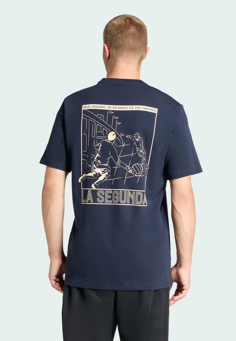 Marineblaues T-Shirt aus Baumwolle mit einer cremefarbenen Grafik auf der Rückseite, die eine Fußballsituation mit dem Text "LA SEGUNDA" zeigt.