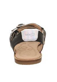 Černé kožené sandály s nastavitelnými popruhy, světlým opalovacím stélkou a texturovanou podrážkou. Na zadní straně se nachází stříbrná logo nášivka.