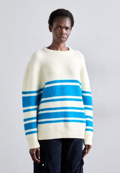 Pull crème avec des rayures bleues et blanches, fabriqué dans un matériau doux, doté d'un col rond et d'un ourlet à côtes.