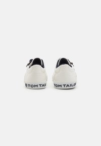 Witte sneakers met een gestructureerde achterkant, marineblauwe accenten en een merkgebonden donkerblauwe hieltab. Kenmerkt zich door een ritssluiting en glad leren materiaal.