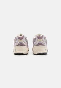 Încălțăminte sport tip lace-up cu un superior din plasă de culoare violet deschis și gri, având o talpă bej texturată și accente reflectorizante în spate.