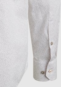 Witte shirt met een subtiel patroon van kleine rode en beige vormen, met een knoopmanchet en een gladde stoftextuur.