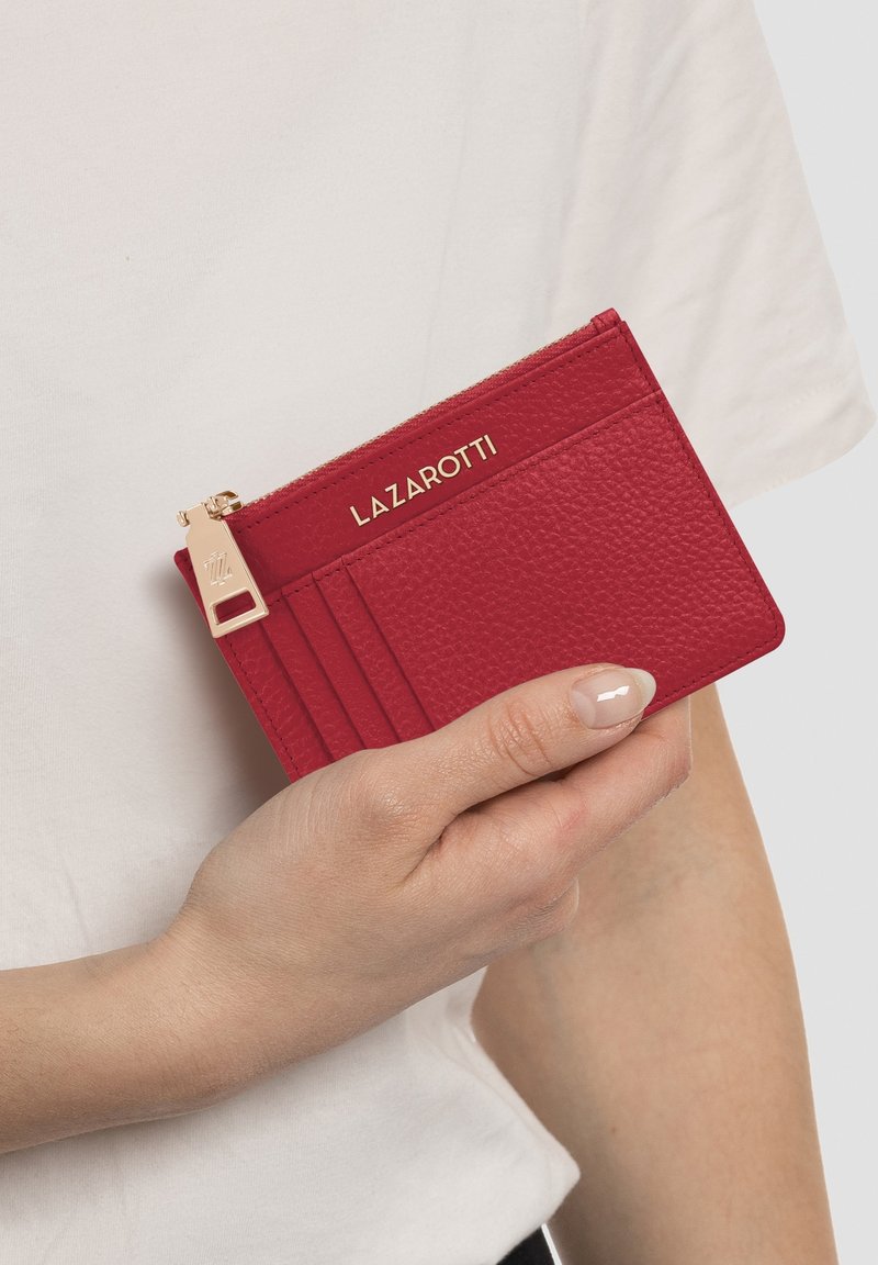 Portafoglio in pelle rossa con finitura testurizzata, multiple slot per carte, hardware in tonalità oro e chiusura con zip con dettaglio del marchio.