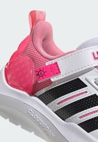 Chaussure de sport rose et blanche avec une tige en mesh, des accents noirs, une étiquette LED, et un talon en caoutchouc texturé pour une meilleure adhérence. Dispose d'une fermeture à bride velcro.