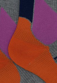 Calzini multicolori con base grigia e motivi geometrici arancioni, viola e blu navy, caratterizzati da una texture a coste e un design distinto.