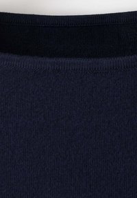 Gros plan d'un tissu tricoté côtelé bleu marine foncé montrant la texture détaillée et les coutures de l'encolure.