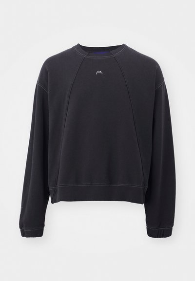 Melnā džemperis ar apaļu kakla izgriezumu, raglan piedurknēm un ribota apakšmala. Iezīmēts ar šūtu apakšmalu un mazu logotipu priekšpusē.