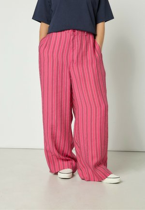 Ružové pruhované široké nohavice vyrobené z ľahkej látky, so zvlášť dvomi bočnými vreckami a uvoľneným strihom. Ozdobené vertikálnymi bielymi pruhmi.