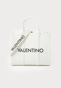 Biała torba na ramię z płócienka z wyraźnym czarnym napisem "VALENTINO", podwójnymi uchwytami oraz odpinanym paskiem. Prostokątny kształt z pionowymi przeszyciami.