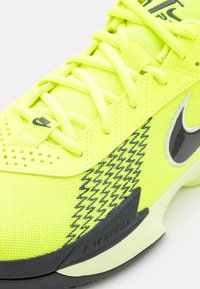 Limegul sportssko med mesh-overdel, forsterket tå, svart houndstooth-mønster på siden og Nike swoosh-logo. Zoom-demping er synlig.