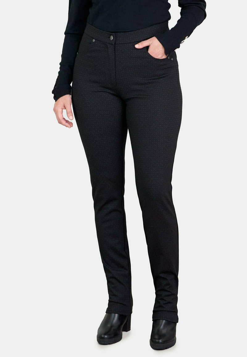 Pantalones negros con un patrón texturizado, diseño ajustado, bolsillos delanteros y cierre de botón, combinados con botas de tacón negras.
