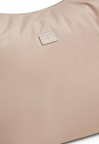 Borsa a mano in nylon beige chiaro con una superficie liscia, dotata di una placca rettangolare in argento con logo e una chiusura con zip lungo la parte superiore.