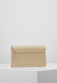 Guld-färgad clutchväska med en slät, metallisk yta, rektangulär form, en vikflik och kedjedetalj. Minimalistisk design utan synliga mönster.