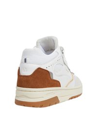 White and brown sneaker with suede heel, perforated side panels, and textured rubber sole, viewed from back left angle.