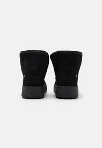 Schwarze Wildlederstiefeletten mit strukturiertem Finish, abgerundetem Schaft und Gummisohle. Mit Branding an der Ferse und einfachen Nähakzenten.