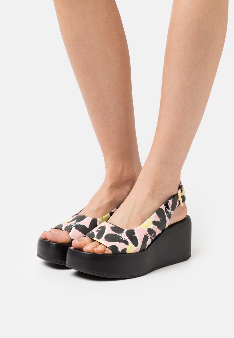 Sandales à plateforme avec une semelle noire, dotées d'une tige en tissu rose ornée de motifs abstraits noirs et jaunes, et d'une bride arrière.