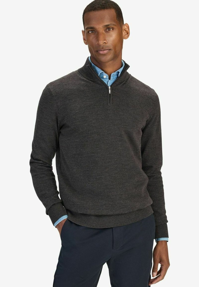 Hiha-paita, jossa on vetoketju, hiiliväri, neulottu materiaali, ribbireunat hihoissa ja vyötärössä, yhdistettynä vaaleansiniseen kauluspaitaan.