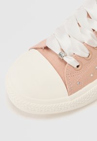 Sneaker in tela rosa chiaro con punta in gomma bianca, dotato di lacci in nastro di raso, dettagli in acciaio inossidabile e piccoli strass.