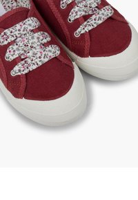 Sneakers in tela rossa con suole in gomma bianca e lacci con motivo floreale. Il tessuto presenta una finitura testurizzata con dettagli di cucitura a contrasto.