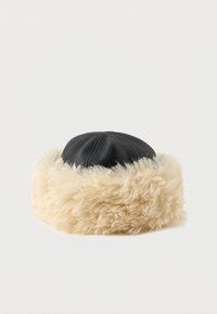 Black leather cap with a fluffy beige faux fur brim, featuring a rounded shape and textured appearance. Suitable for cold weather.
