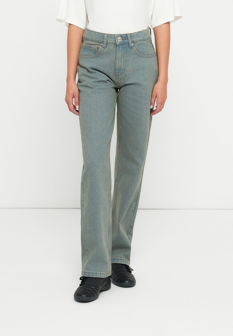 Ανοιχτογάλαζα τζιν παντελόνια με ψηλή μέση, ευθεία γραμμή, διακριτική φθορά και κλείσιμο με κουμπί μπροστά. Συνδυασμένα με μαύρα παπούτσια.