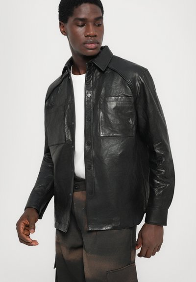 Black leather shirt jacket with a button-up front, two chest pockets, and a structured collar. Patterned texture adds visual interest.