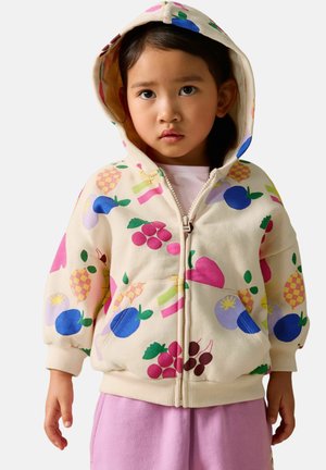 Hættetrøje med lynlås i cremefarve med farverige frugtmønstre. Leveres med ribstrikkede manchetter og kant. Kombineret med lyserøde joggingbukser.