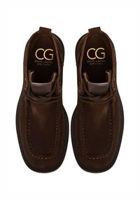 Paire de bottines en daim brun foncé avec surpiqûres décoratives et semelles intérieures dorées "CG Cesare Gaspari Barcelona", vue de dessus.