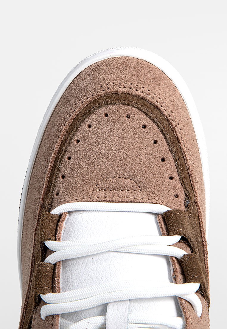 Brązowe zamszowe sneakersy z białymi skórzanymi akcentami, okrągły nosek i płaskie białe sznurówki. Posiada perforacje oraz kontrastujące ciemnobrązowe detale.
