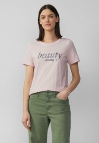 T-shirt rose clair à manches courtes avec une broderie texturée portant l'inscription "la beauté d'être". Assorti à un pantalon vert, offrant une coupe décontractée.