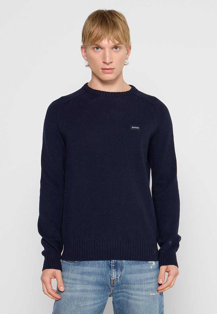Pull en tricot bleu marine à col rond, avec des poignets et un ourlet côtelés. Présente un petit patch logo sur la poitrine gauche. Tissu doux et texturé.