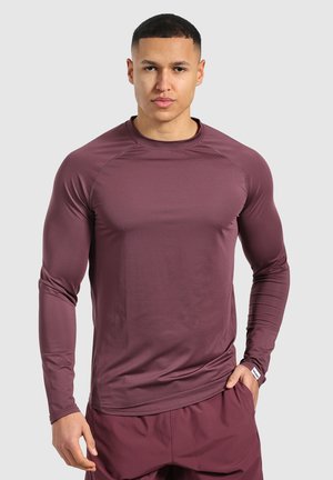 Camiseta atlética de manga larga en granate oscuro, hecha de un tejido suave y elástico, con mangas raglán y un corte ajustado.