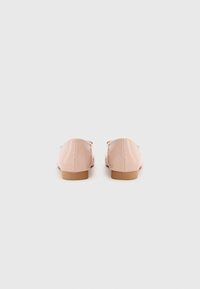 Pink patent leather loafers with a rounded toe and small heel. Smooth texture, minimalistic design, and a tan rubber sole for grip.
