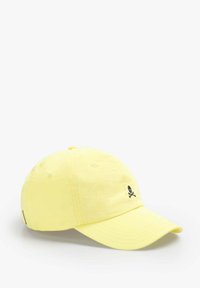 Yellow cotton cap with a curved brim, featuring a black skull and crossbones logo on the front and ventilation eyelets on the sides.
