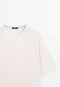 Lichtroze t-shirt met korte mouwen en ronde hals, gemaakt van zachte stof. Heeft een eenvoudig ontwerp en een label op de hals.