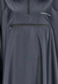 Mørkeblå vandtæt jakke foran med vandret lynlåslomme på brystet og "Swedemount" logo på højre side.