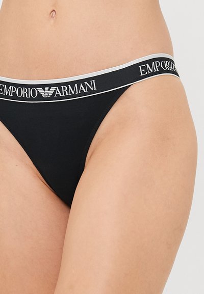 Zwart thong ondergoed van zacht materiaal met een elastische tailleband, voorzien van witte letters "Emporio Armani" en een logo.