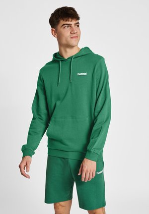 Grøn hættejakke lavet af blødt stof, med en frontlomme og snørehætte, ledsaget af matchende shorts med logo-detalje.