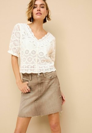 White lace blouse with short sleeves and scalloped neckline, paired with a faded brown denim skirt featuring frayed hem and front pockets.