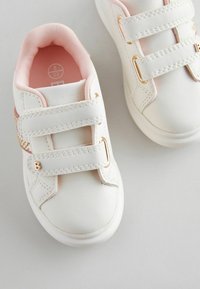 Weiße Ledersneaker mit rosa Akzenten, ausgestattet mit zwei Klettverschlüssen, goldfarbener Hardware und einer glatten, strukturierten Oberfläche.