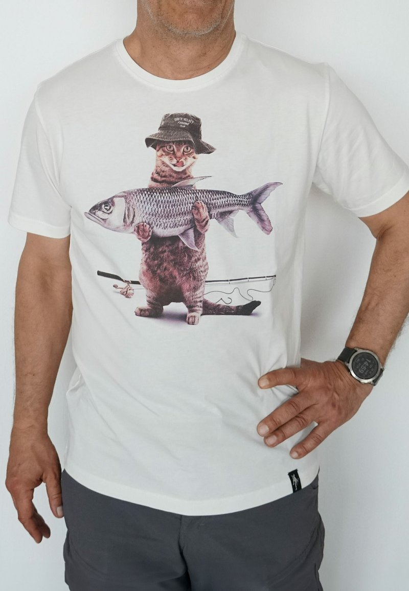 White cotton t-shirt featuring a graphic of a cat wearing a bucket hat, holding a large fish, with a fishing rod in the background.